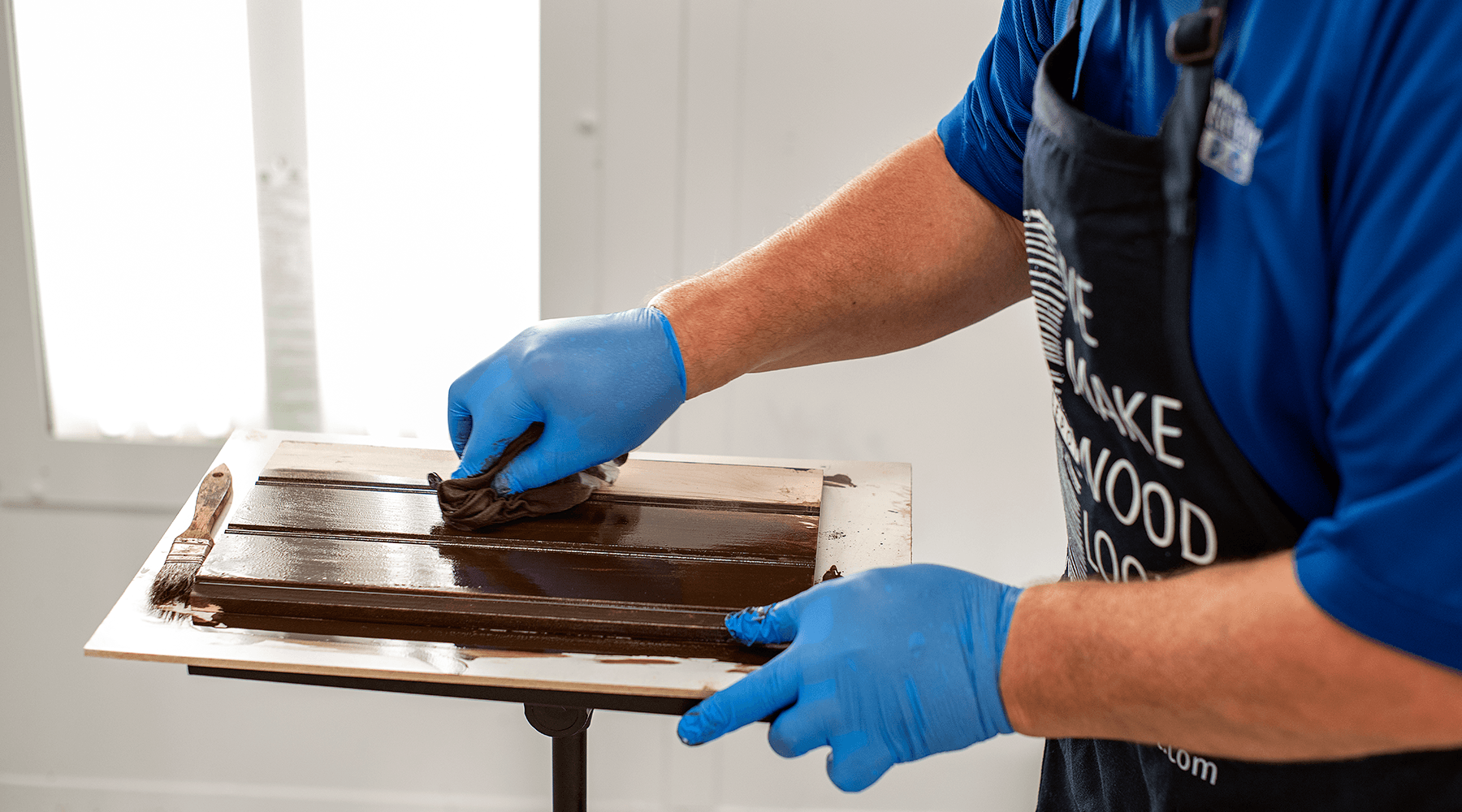 A wood stain specialist staining a piece of wood